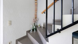 A staircase with a handrail, a wall-mounted ladder, and decorative items including a vase with flowers and small figurines. - Apartment 'Haus Sünnschien' with Shared Terrace, Shared Garden and Wi-Fi (Nordstrand)