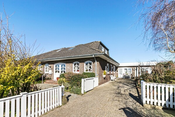 Ein zweistöckiges Haus mit geneigtem Dach, einer Veranda und einer Auffahrt zu einem verschlossenen Eingang.