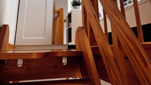 Une chaise en bois avec un plateau en métal, dans une pièce dotée d’une porte blanche et d’une fenêtre.
