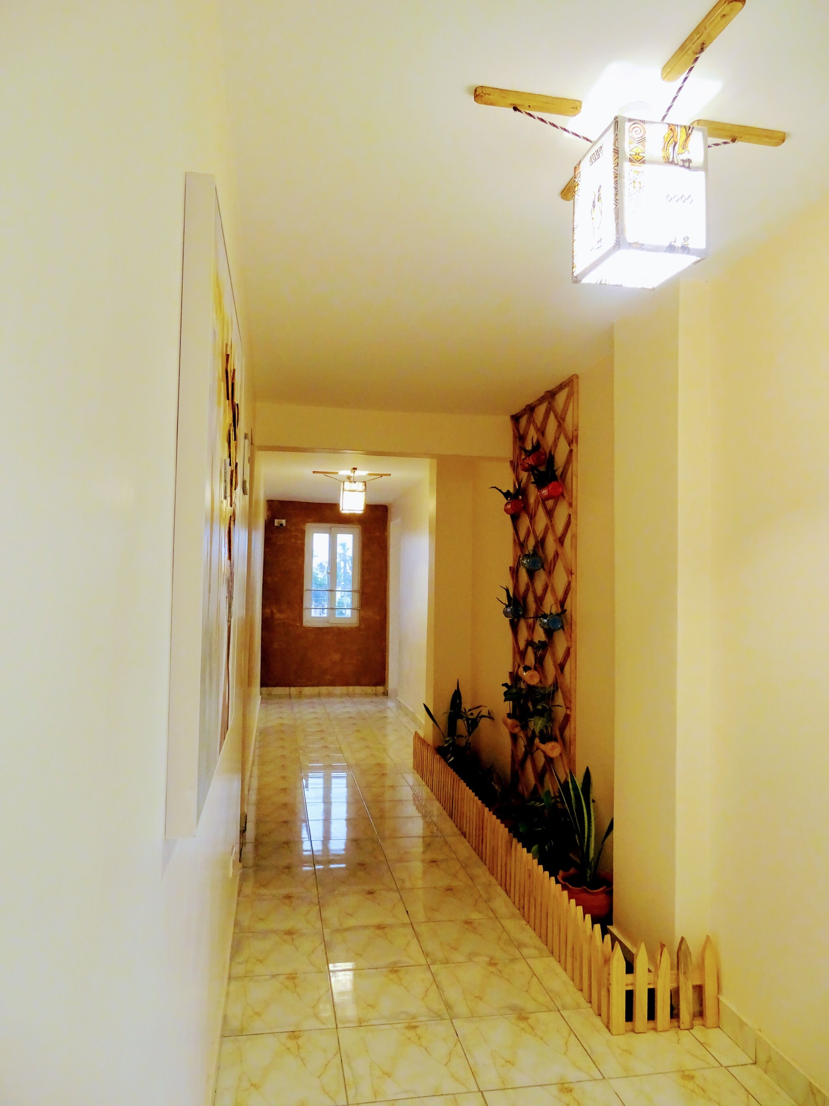 A hallway with a ceiling fan, a wooden fence, and a wall-mounted decorative panel.
