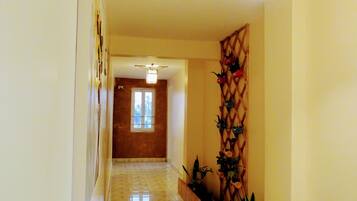 A hallway with a ceiling fan, a wooden fence, and a wall-mounted decorative panel.