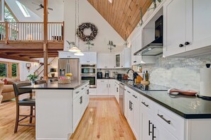 Una cocina amplia con armarios blancos, techo de madera y vistas al exterior.