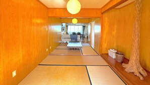 Um interior japonês tradicional com esteiras de tatame, teto de madeira e um lanterna de papel pendurada.