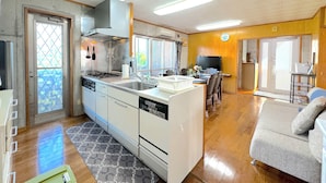 Cozinha compacta com ilha central, área de refeições com sofá e uma grande janela que oferece luz natural.