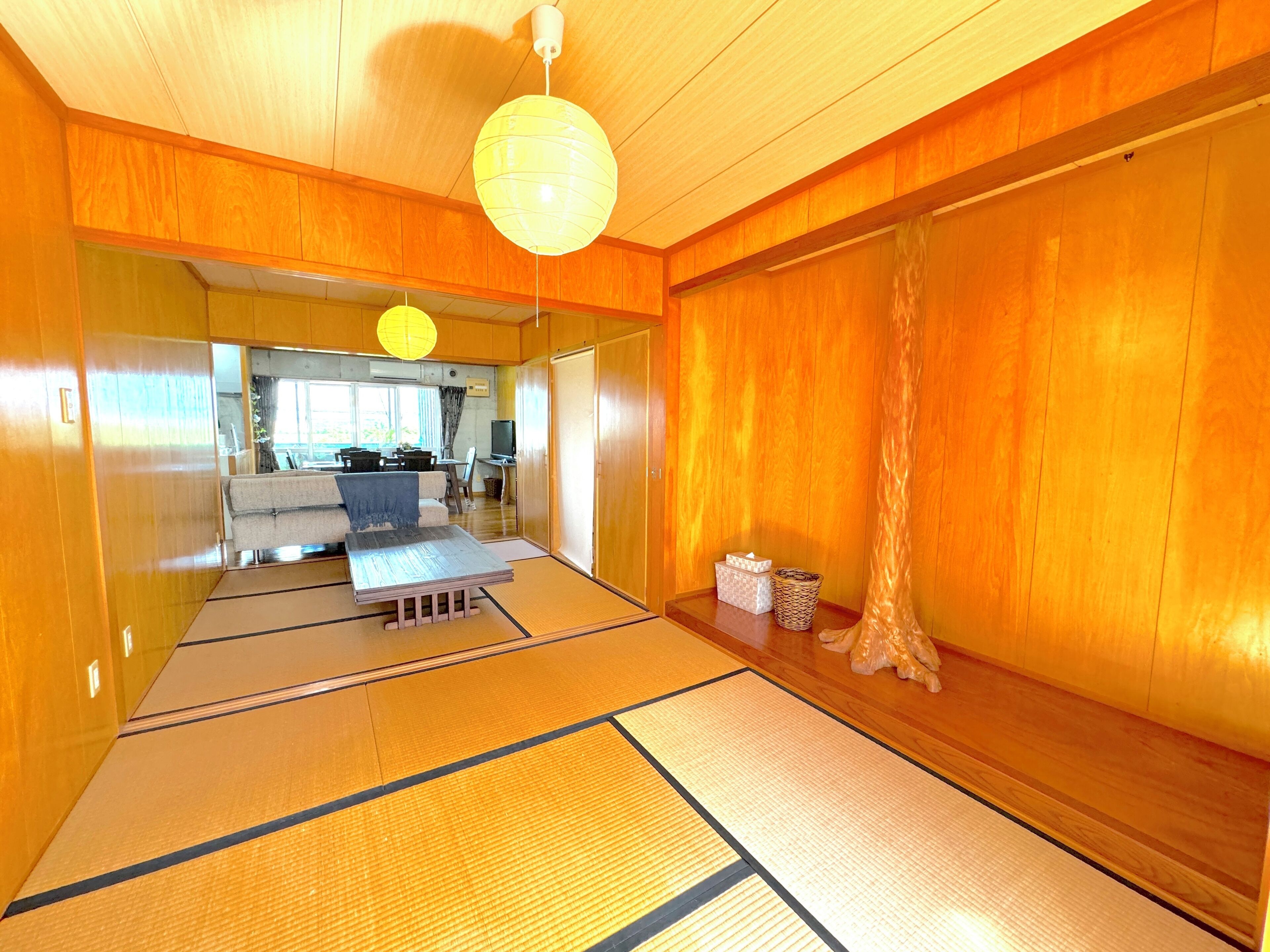 Une pièce de style japonais traditionnel, avec un sol recouvert de tatamis, une table basse, un canapé et une porte coulissante.