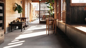 A corridor with wooden walls, a concrete floor, and a wooden table with chairs. - NIPPONIA KOSA CANAL TOWN (Kosa)