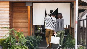 A wooden building entrance with a large white banner, potted plants, and a metal fence.