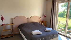 A bedroom with a bed, two bedside tables with lamps, a window with a view of greenery, and a wooden ceiling. - Une Maison en Bois du Québec Près de Nevers, Moulins, le Pal et les Canaux ! (Saint-Germain-Chassenay)