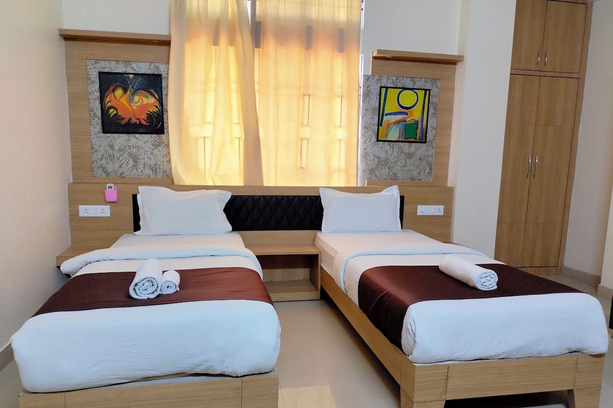 Quarto de casal com duas camas, guarda-roupa e obras de arte nas paredes.