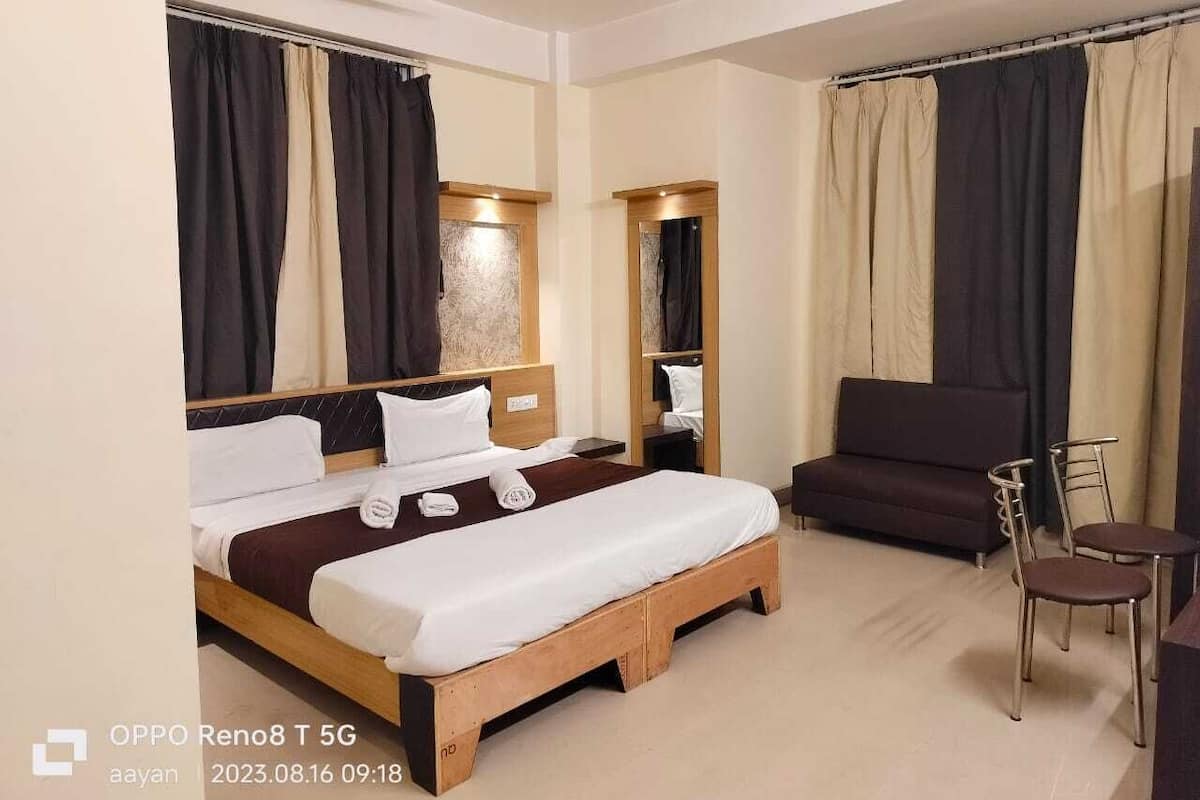 Quarto de hotel com cama, sofá, poltrona e uma pequena mesa.