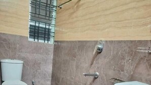 A bathroom with a toilet, sink, and shower area. - Hotel Jaysha (Guwahati)
