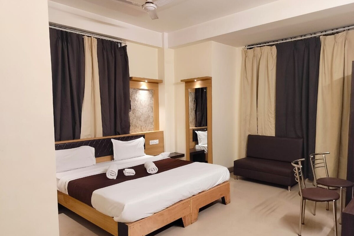 A hotel room with a bed, a sofa, a chair, and a small table.