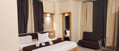 A hotel room with a bed, a sofa, a chair, and a small table.