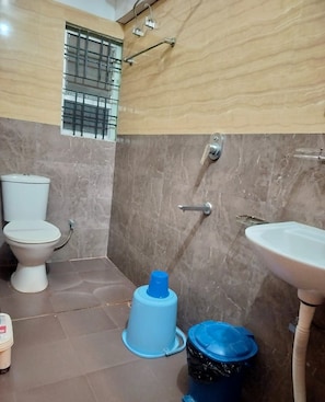 A bathroom with a toilet, sink, and shower area. - Hotel Jaysha (Guwahati)