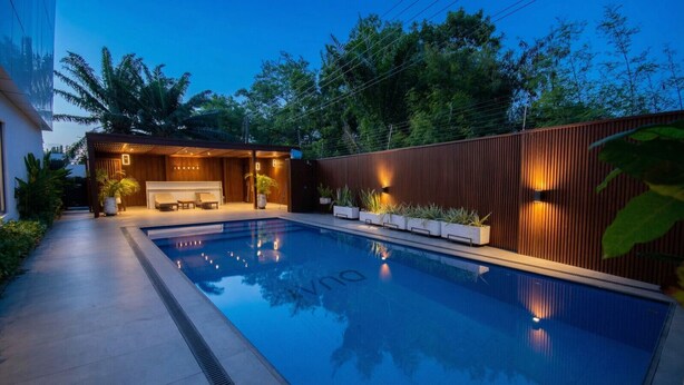 A swimming pool with a wooden deck, a covered seating area, and a wooden fence. - Oasis Retreat at 233 Boulevard (Accra)