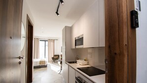 A modern hotel room with a kitchen area, including a microwave, oven, and a sink. - Oasis Retreat at 233 Boulevard (Accra)