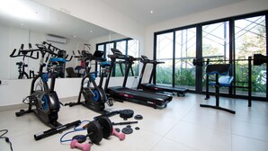 A home gym with exercise equipment, including treadmills, an elliptical, and free weights. - Oasis Retreat at 233 Boulevard (Accra)