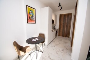 Een gezellig eetgedeelte met een ronde tafel en twee stoelen, een keuken met een houten deur en een marmeren vloer.
