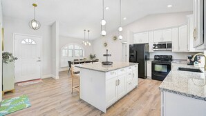 A spacious kitchen with white cabinetry, a large island, and modern appliances.
