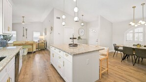 A spacious kitchen with a central island, wooden flooring, and pendant lighting.