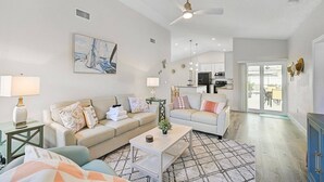 A spacious living room with a sofa, coffee table, and a painting on the wall.