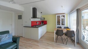 A compact living space with a kitchenette, dining area, and a sofa. - Beach House in Callantsoog near Scenic Beach (Callantsoog)