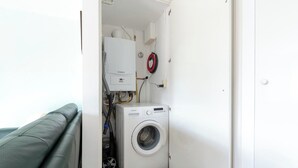 A compact laundry room with a washing machine, a heater, and a hose. - Beach House in Callantsoog near Scenic Beach (Callantsoog)