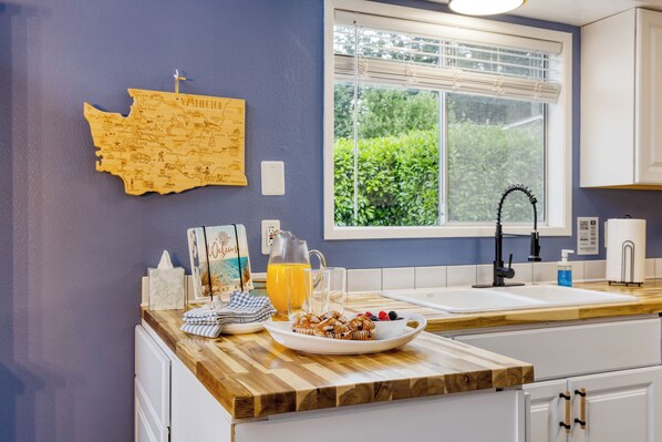 A kitchen with a wooden countertop, a sink, and a window with a view of greenery.