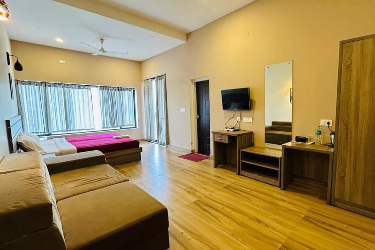 Una habitación de hotel moderna con una cama grande, un sofá, un televisor, un armario y un escritorio.