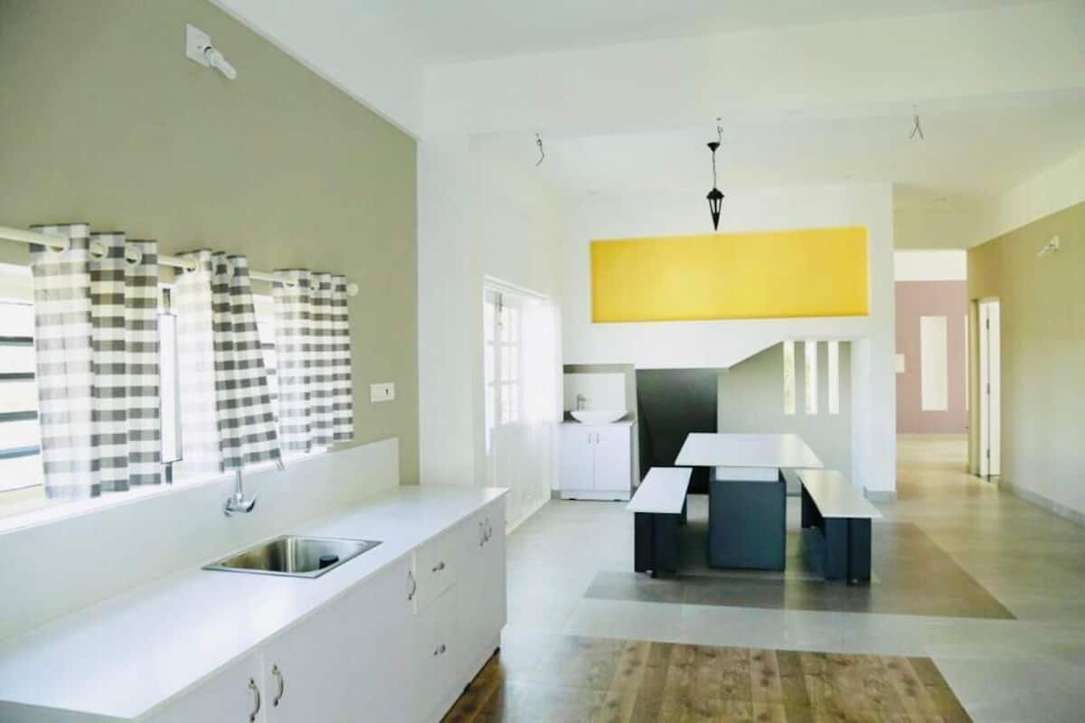 Una cocina moderna con encimera blanca, pileta integrada y ventana con cortinas a cuadros.