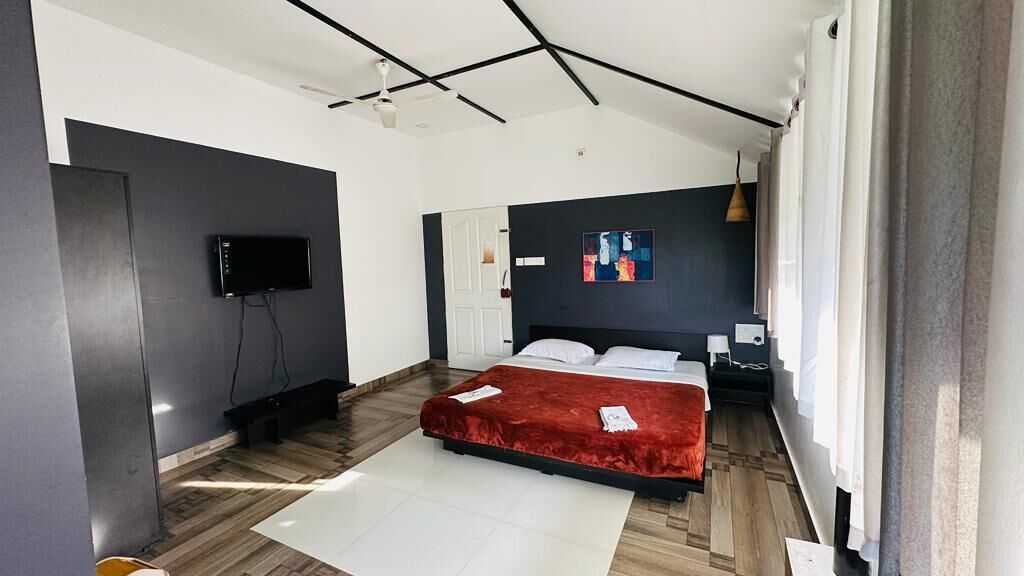Un dormitorio moderno con cama, televisor de pantalla plana, un cuadro en la pared y una ventana con cortinas.