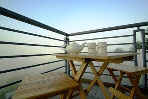 Enjoy a scenic view from this balcony with a table and bench, perfect for a morning tea.