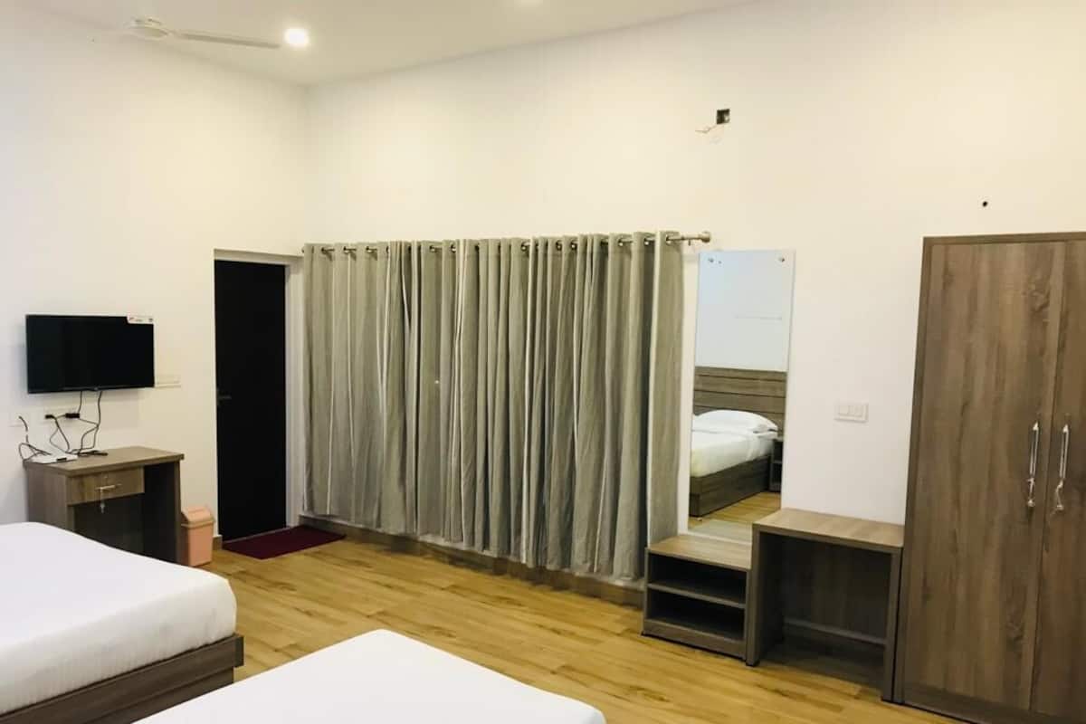 Una habitación de hotel con dos camas, televisión, armario y espejo.