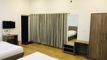 A hotel room with two beds, a television, a wardrobe, and a mirror.