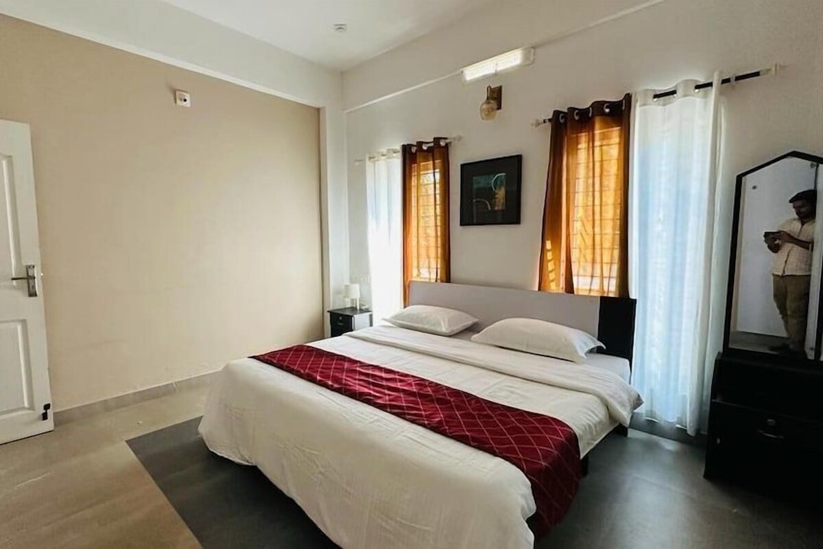 A bedroom with a bed, a nightstand, a dresser, and a door.