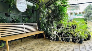 Relax in a serene outdoor space surrounded by lush greenery and a unique bicycle wheel feature.