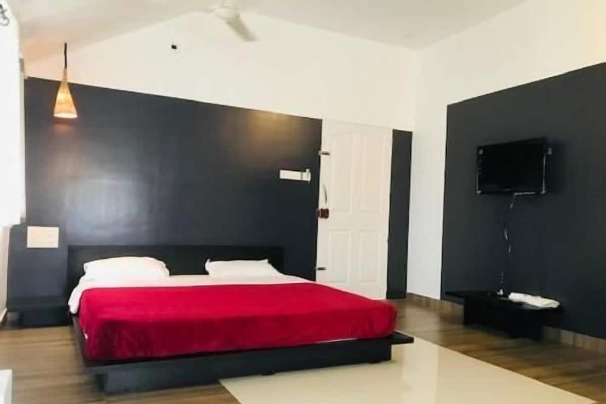 Un dormitorio con una cama, un televisor de pantalla plana, una puerta y un ventilador de techo.