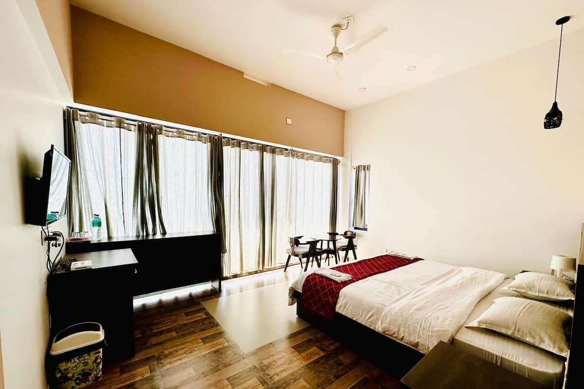 Una habitación de hotel con una cama, un escritorio, una silla, una mesita y un ventilador de techo.