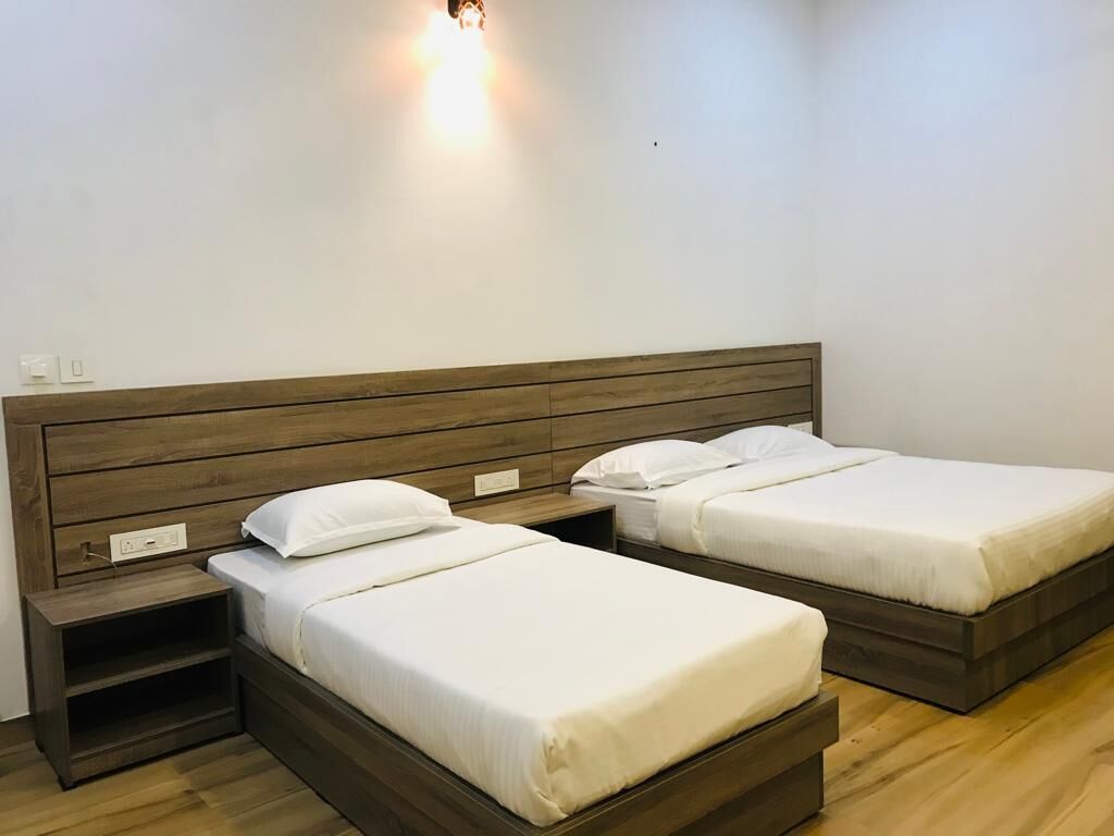 A bedroom with two beds, wooden headboards, and bedside tables.