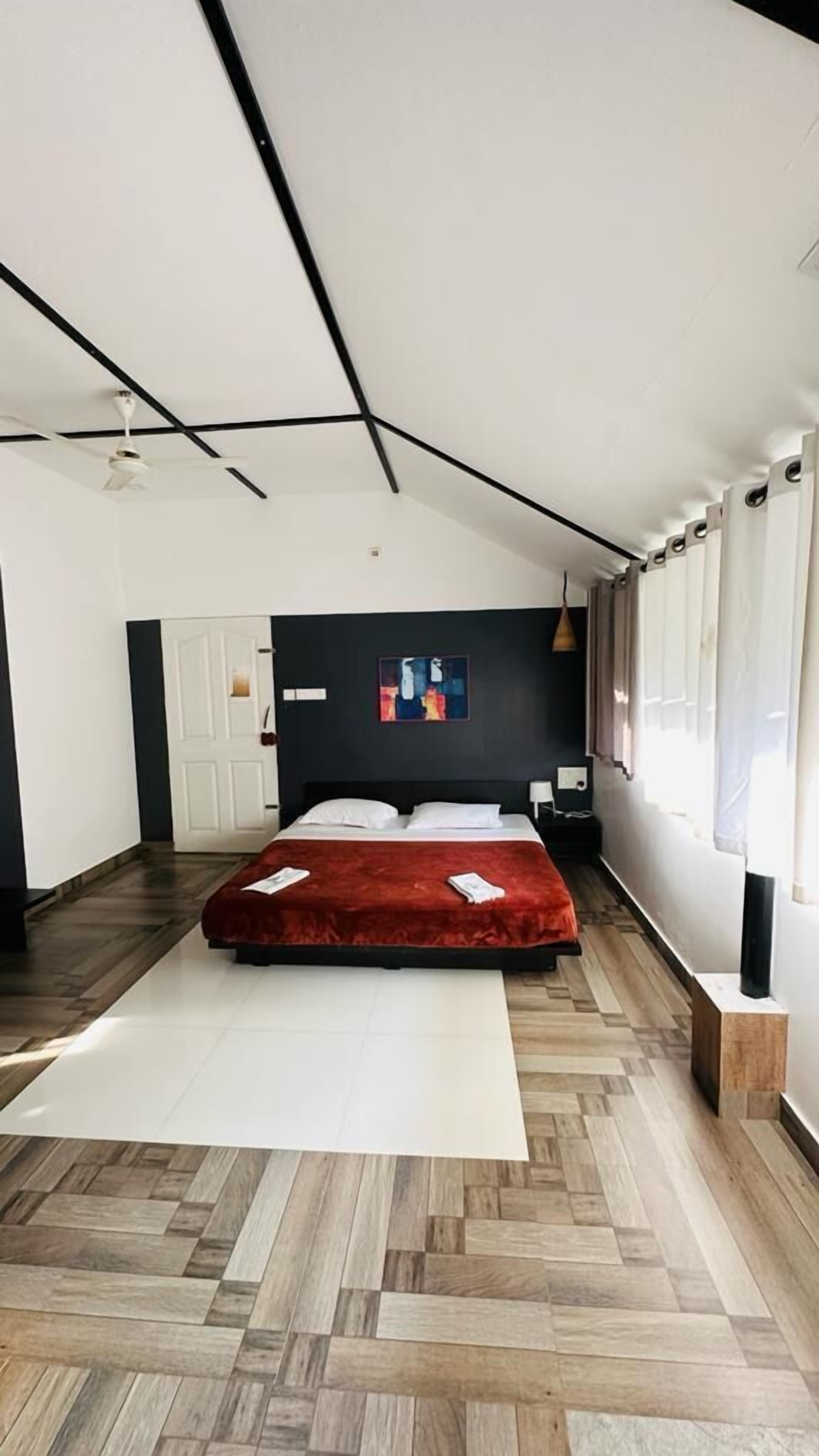 A modern bedroom with a bed, a ceiling fan, and a large window.