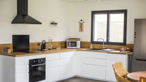 Eine moderne Küche mit Kochinsel, integriertem Backofen, Mikrowelle und einem großen Fenster für natürliches Licht.