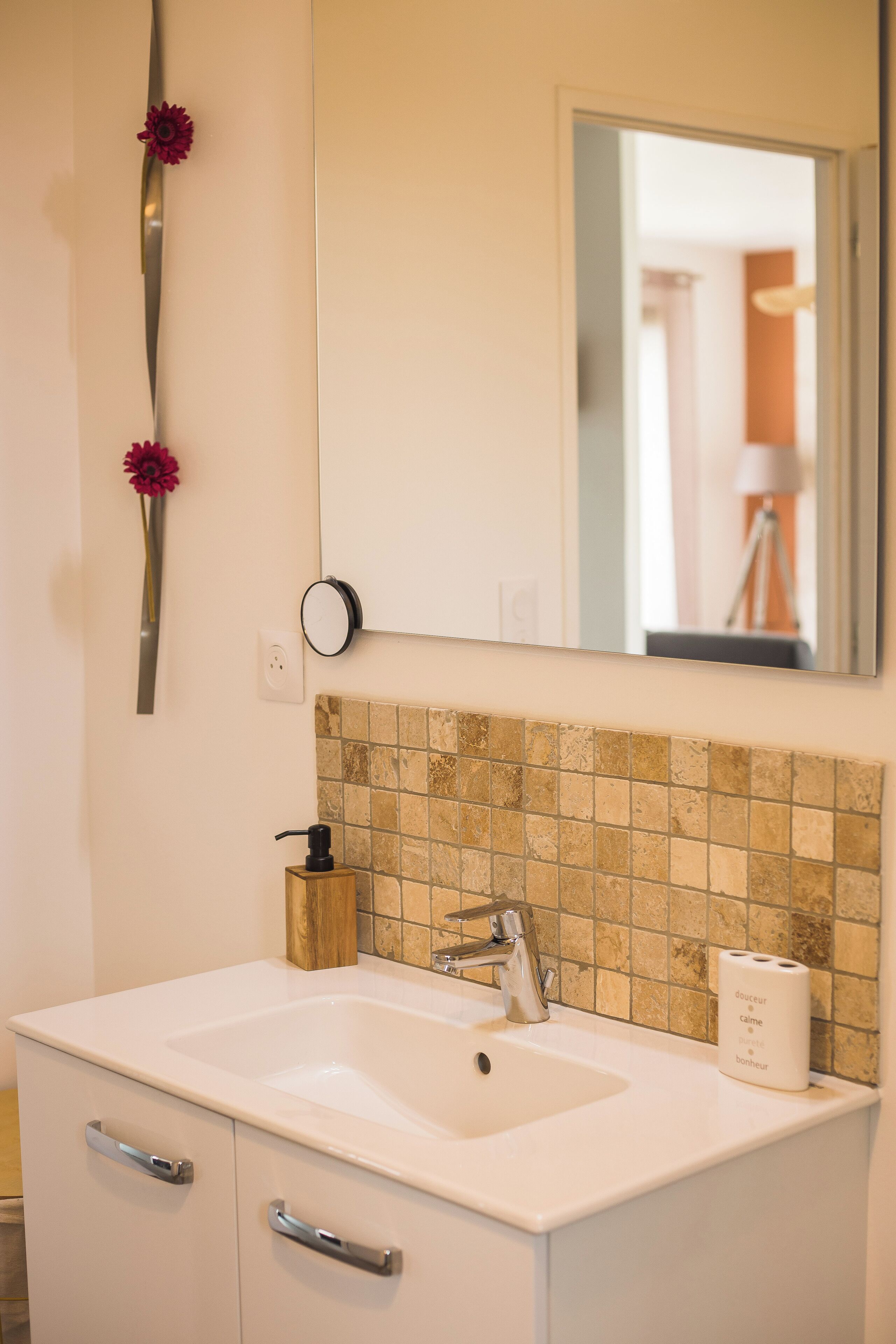 A bathroom with a white sink, a mirror, and a tiled backsplash.