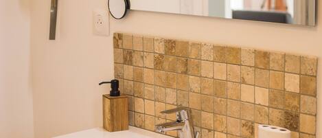A bathroom with a white sink, a mirror, and a tiled backsplash.