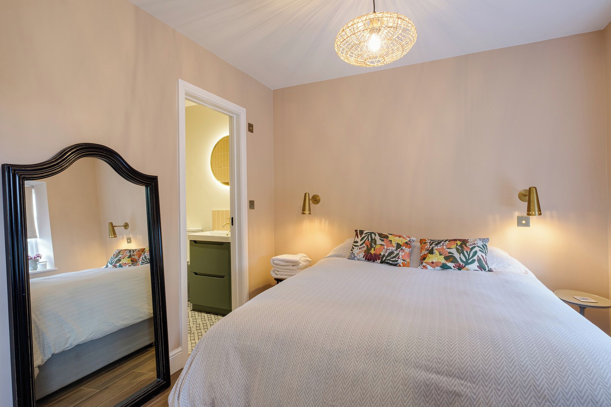 Ein Schlafzimmer mit einem großen Bett, einem Spiegel, einem Nachttisch und einer Hängelampe.