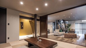 A modern living room with a wooden coffee table, a sofa, and a staircase leading to another level. - JAPAVISTA Radiant (Osaka)