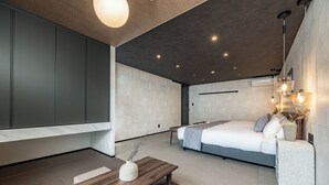 A modern bedroom with a bed, bedside table, and a hanging light fixture. - JAPAVISTA Radiant (Osaka)