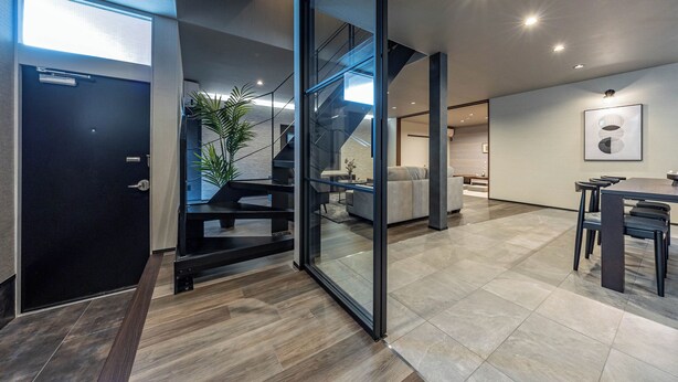 A modern interior with a staircase, a dining area, and a large glass door leading to another room. - JAPAVISTA Radiant (Osaka)