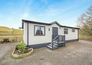 Ein Bungalow mit Veranda, einer Tür und zwei Fenstern.