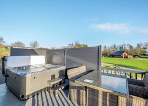 A hot tub with a glass top, surrounded by wicker furniture on an outdoor deck. - Nith Valley Lodge Pet (Dumfries, Dumfries & Galloway)