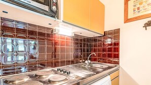 Une cuisine équipée d’une cuisinière en acier inoxydable, d’un four à micro-ondes et d’un évier.
